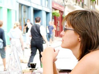 Woman wearing glasses looking across an outdoor café